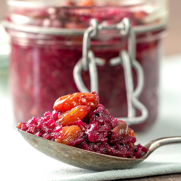 Square image of a red cabbage chutney with apples and raisins with a serving sat on a vintage spoon