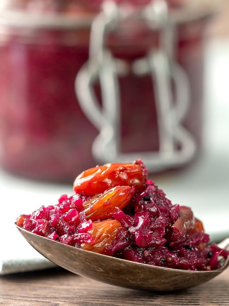 Portrait close up image of a red cabbage chutney with apples and raisins with a serving sat on a vintage spoon