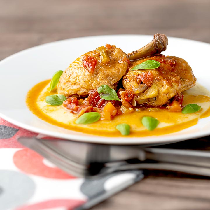 Square image of slow cooker chicken cacciatore served on a bed of polenta