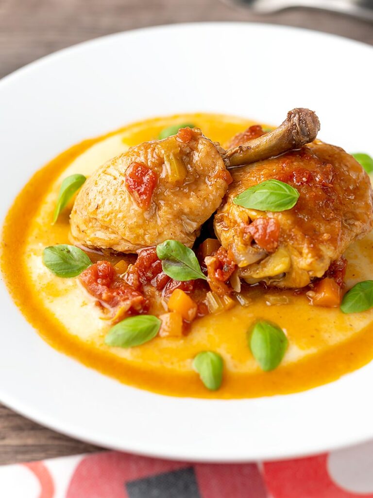 Portrait image of slow cooker chicken cacciatore served on a bed of polenta
