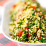 Portrait shallow depth of field image of a herby tabbouleh salad served in a white bowl with text overlay