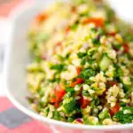 Portrait shallow depth of field image of a herby tabbouleh salad served in a white bowl with text overlay