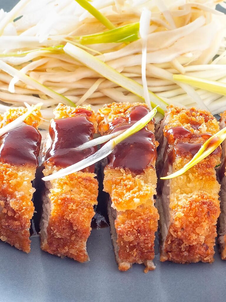 Portrait close up image of pork tonkatsu with homemade katsu sauce served with Japanese shredded cabbage