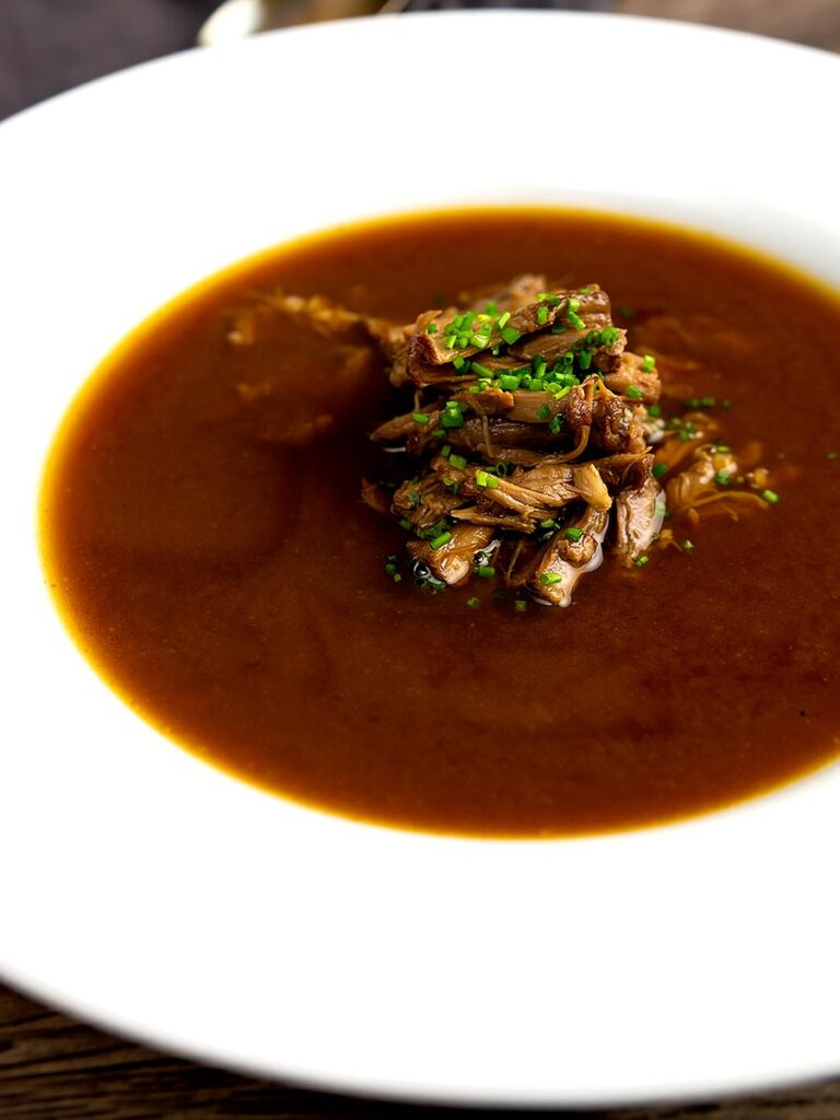 Portrait image of shredded beef in a classic British oxtail soup