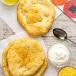 Portrait overhead image of Hungarian fried bread or Langos ready to be topped with sour cream, cheese and garlic oil