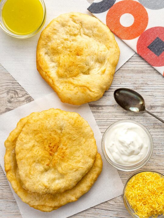 Portrait overhead image of Hungarian fried bread or Langos ready to be topped with sour cream, cheese and garlic oil