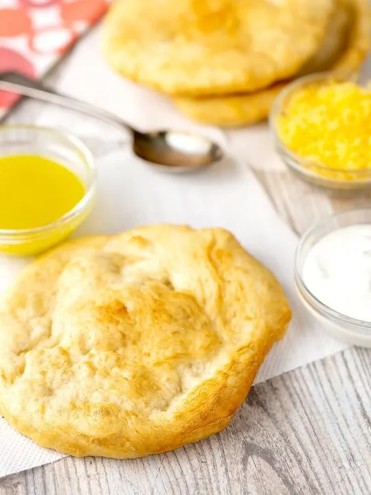 Portrait image of Hungarian fried bread or Langos ready to be topped with sour cream, cheese and garlic oil