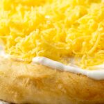 Portrait close up image of Hungarian fried bread or langos topped with sour cream and cheese