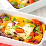 Portrait image of Mediterranean baked feta cheese with tomatoes and peppers served in a white gratin bowl