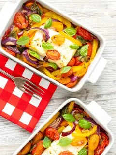 Portrait image of Mediterranean baked feta cheese with tomatoes and peppers served in a white gratin bowl