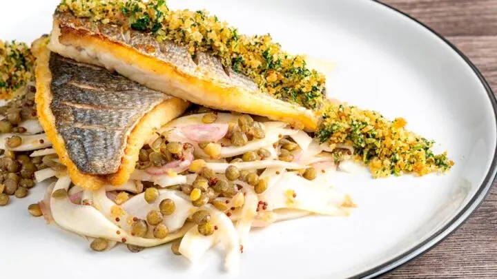 Landscape image of pan fried sea bream fillet served with a parsley crumb and puy lentils with fennel