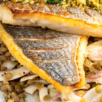 Portrait close up image of pan fried sea bream fillet served with a parsley crumb and puy lentils with fennel with text overlay