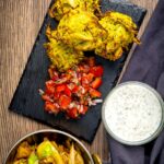 Portrait overhead image of crispy air fryer onion bhaji or pakora served with a curry and mint and yoghurt dip