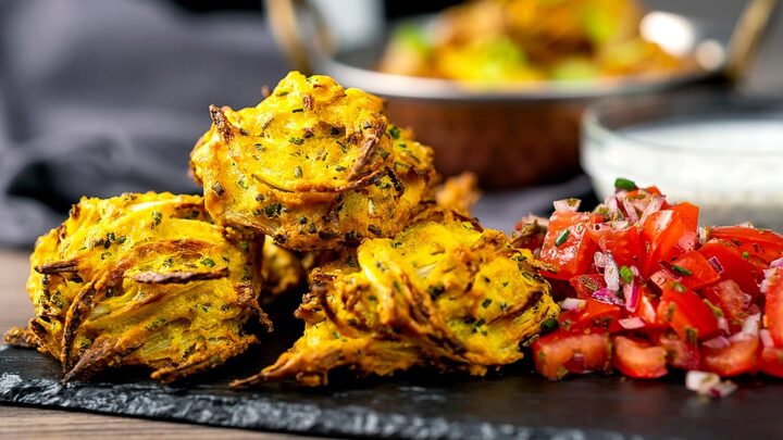 Landscape image of crispy air fryer onion bhaji or pakora served with a curry and mint and yoghurt dip