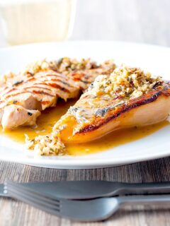 Portrait image of a savoury baked pears side dish in a cider sauce served on a white plate