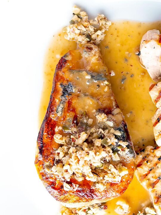 Portrait overhead image of a savoury baked pears side dish in a cider sauce served on a white plate