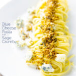 Portrait image of a blue cheese pasta recipe featuring spaghetti coated in garlic butter, a buttery sage crumb and Gorgonzola cheese with a text overlay
