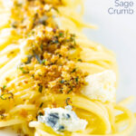 Portrait close up image of a blue cheese pasta recipe featuring spaghetti coated in garlic butter, a buttery sage crumb and Gorgonzola cheese with a text overlay