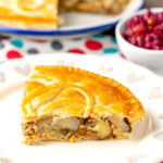 Portrait image of a slice of cheese and onion pie with potatoes and mustard served on a plate with the rest of the pie in the background with a text overlay