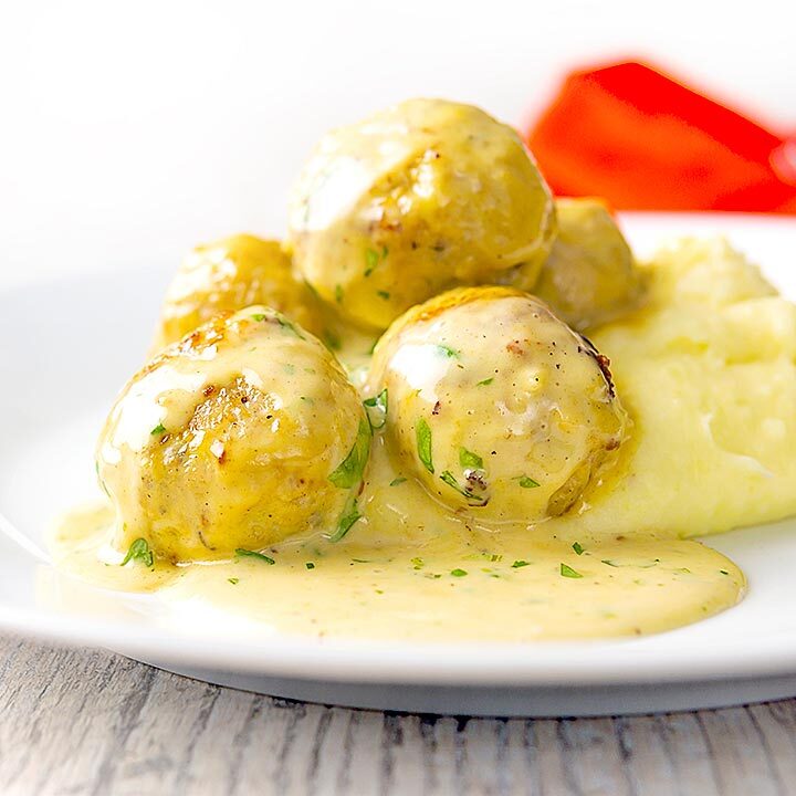 Square image of chicken meatballs in a creamy honey and mustard sauce served with mashed potatoes