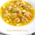 Portrait image of an simple pork meatball soup in a golden vegetable broth served in a white bowl