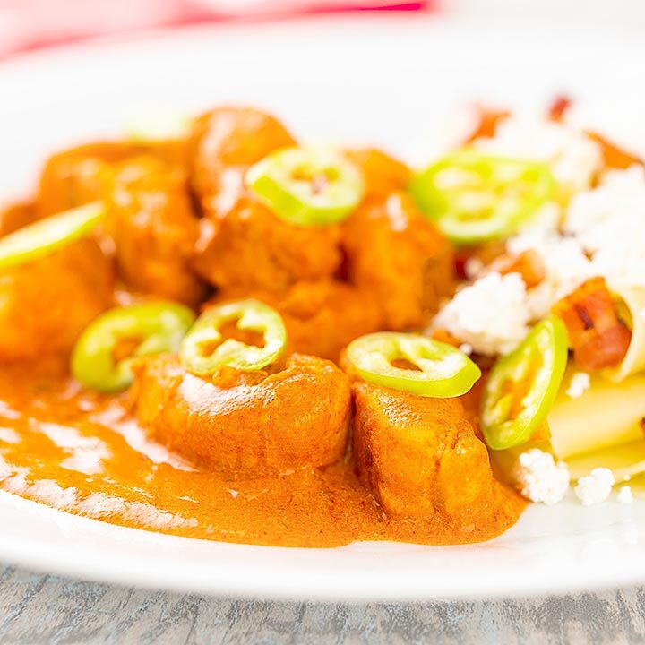 Square image of a Hungarian fish paprikash or harcsapaprikas served on a white plate in a silky paprika rich sauce