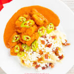 Portrait overhead image of a Hungarian fish paprikash or harcsapaprikas served on a white plate in a silky paprika rich sauce with a text overlay