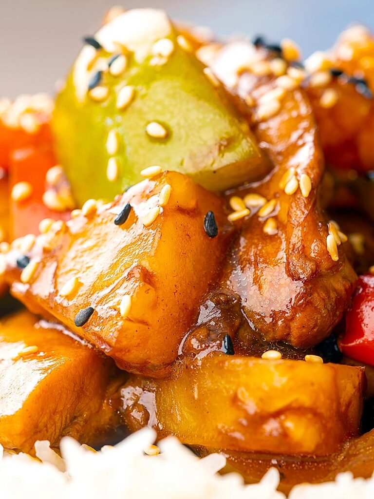 Portrait close up image of a Chinese influenced sweet and sour pineapple chicken dish served with white rice
