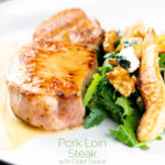 Portrait close up image of a pork loin steak in a cider sauce served on a white plate with a pear and blue cheese salad with a text overlay