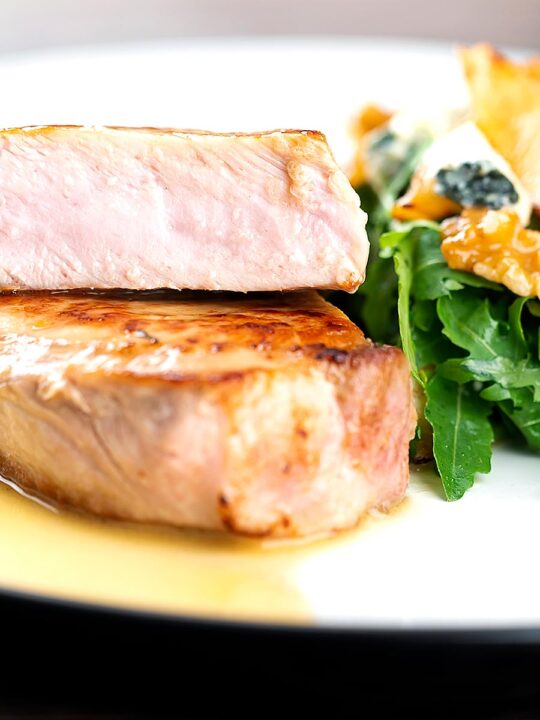 Portrait close up image of a pork loin steak sliced to show the moist interior