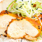 Portrait close up image of a sliced steamed chicken breast cooked in a spicy Korean gochujang marinade served on white rice with a text overlay