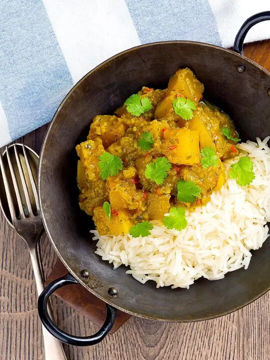 Portrait overhead image of a Burmese influenced vegan pumpkin curry served with white rice and fresh coriander