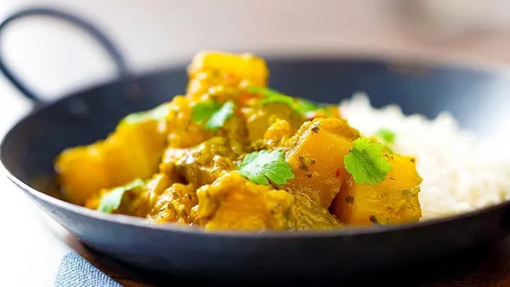 Landscape image of a Burmese influenced vegan pumpkin curry served with white rice and fresh coriander