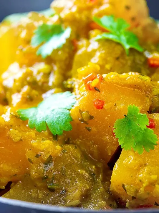 Portrait close up image of a Burmese influenced vegan pumpkin curry served with white rice and fresh coriander