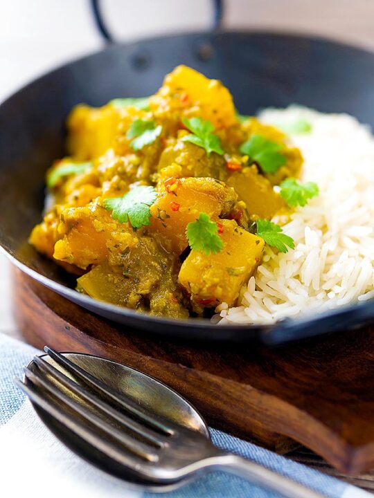 Portrait image of a Burmese influenced vegan pumpkin curry served with white rice and fresh coriander