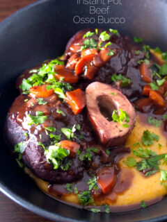 Portrait close up image of a beef shin osso bucco recipe served on polenta in a black bowl with a text overlay