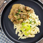 Portrait overhead image of a Hungarian Pork Stew called Borsos Tokany served on a black plate with nokedli noodles