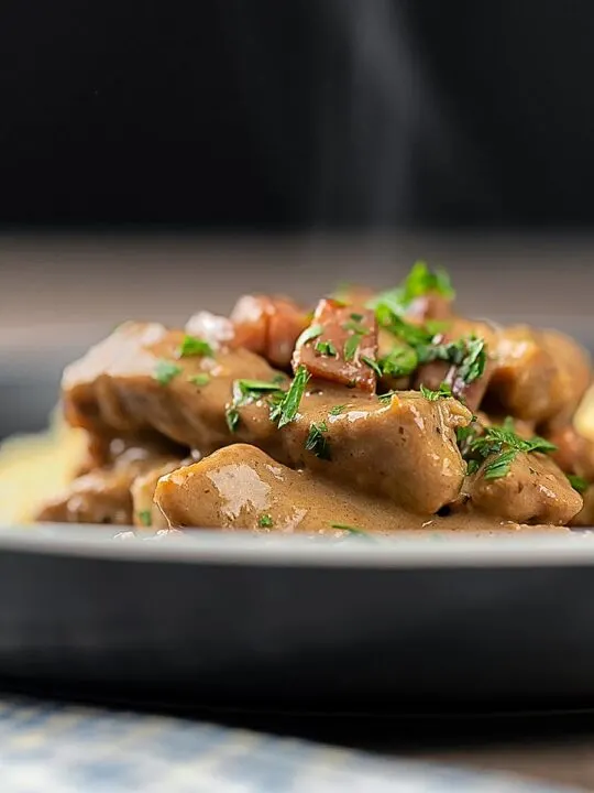 Portrait close up image of a Hungarian Pork Stew called Borsos Tokany served steaming hot with fresh parsley