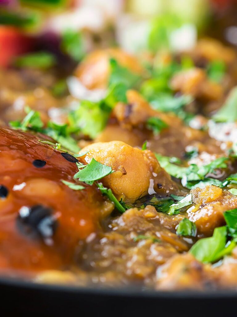Portrait close up image of a vegan chickpea and lentil curry served with mango chutney and kachumber salad