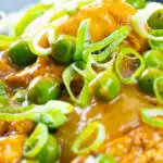 Portrait close up image of a takeaway influenced Chinese chicken curry with garden peas and spring onions featuring a text overlay