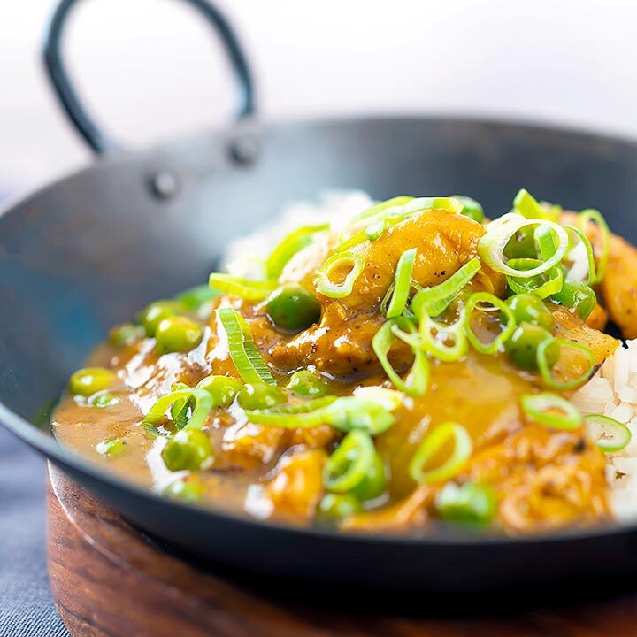 Square image of a takeaway influenced Chinese chicken curry with garden peas and spring onions