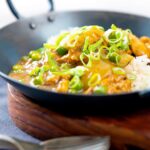Portrait image of a takeaway influenced Chinese chicken curry with garden peas and spring onions