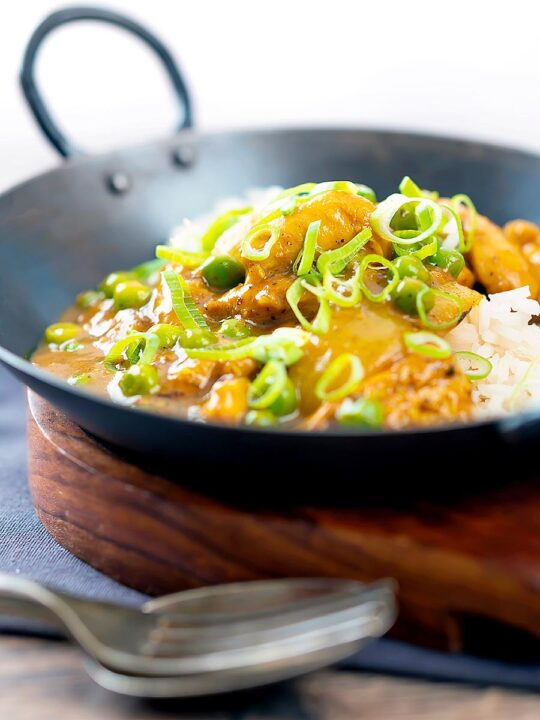 Portrait image of a takeaway influenced Chinese chicken curry with garden peas and spring onions