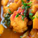 Portrait close up image of a spicy vegetable soup with sweet potato, cauliflower and spinach in a harissa broth