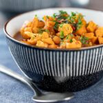 Square image of a spicy vegetable soup with sweet potato, cauliflower and in a harissa broth