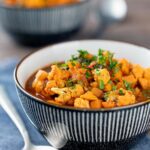 Portrait image of a spicy vegetable soup with sweet potato, cauliflower and in a harissa broth