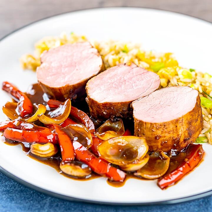 Square image of rosy pink roasted juicy sweet and sour pork tenderloin with onions and red pepper in a rich sweet and sour sauce and egg fried rice