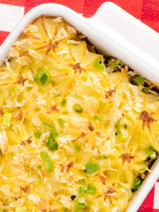 Portrait close up overhead image of an individual cheesy cumberland pie served in a white gratin dish