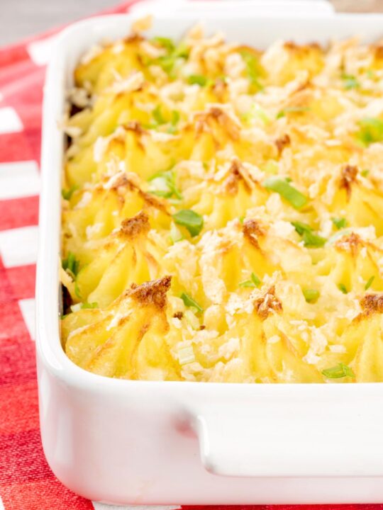 Portrait close up image of an individual cheesy cumberland pie served in a white gratin dish