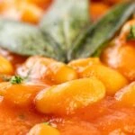 Portrait close up image of Fagioli all&rsquo;uccelletto or Italian Baked Beans served with crispy fried sage leaves
